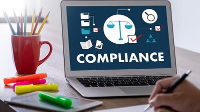 Laptop screen displaying compliance icons and legal symbols, representing annual compliance requirements for businesses.