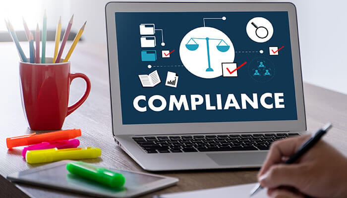 Laptop screen displaying compliance icons and legal symbols, representing annual compliance requirements for businesses.