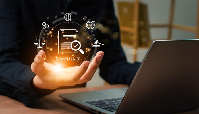 Person using a laptop with digital compliance icons, symbolizing the integration of AI translation tools in regulatory workflows.