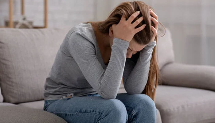 Distressed woman on couch Can I Sue My Neighbor for Emotional Distress?