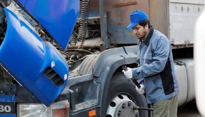 Mechanic inspecting a truck’s tires and engine to prevent mechanical failures that often cause serious truck accidents.
