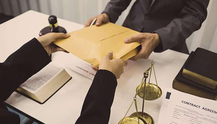 Lawyers exchanging legal documents with scales of justice on desk, showing how police reports in Indiana strengthen accident claims.