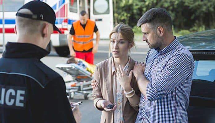 Accident victims speaking with police officer, showing signs of emotional trauma after a serious crash.