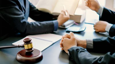Lawyers discussing legal documents related to a generational equity lawsuit with a gavel in the foreground, symbolizing legal proceedings and case discussions.