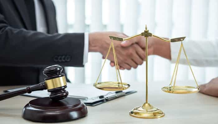 Legal professionals shaking hands with a gavel and scale of justice in the foreground, symbolizing the resolution of business disputes like the Dapper Development Lawsuit.