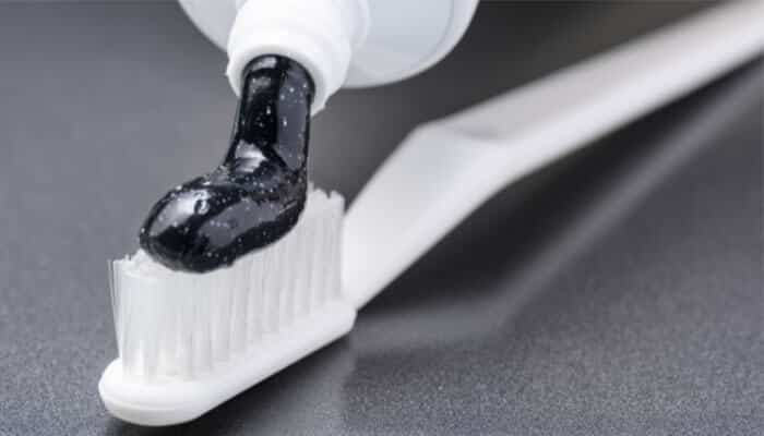 Close-up of black charcoal Hello toothpaste on a toothbrush, linked to safety concerns and claims in the Hello Toothpaste Lawsuit.