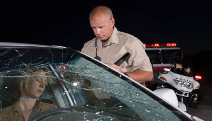 Police officer preparing a report at a car accident scene, highlighting the importance of police reports in Indiana after collisions.