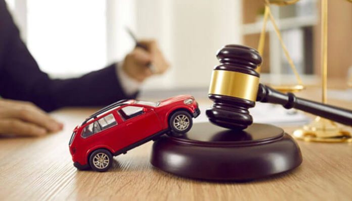 Car accident lawyer concept with toy car on judge’s gavel symbolizing legal help and accident compensation.