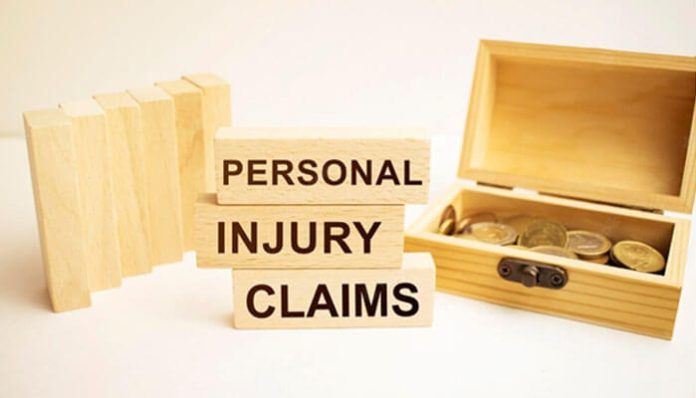 Wooden blocks stacked with the words “Personal Injury Claims” beside an open box of coins, symbolizing compensation and legal claims process.