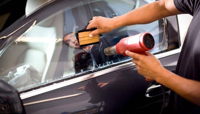 Car window tinting process with heat gun and film application, illustrating compliance with California window tint law