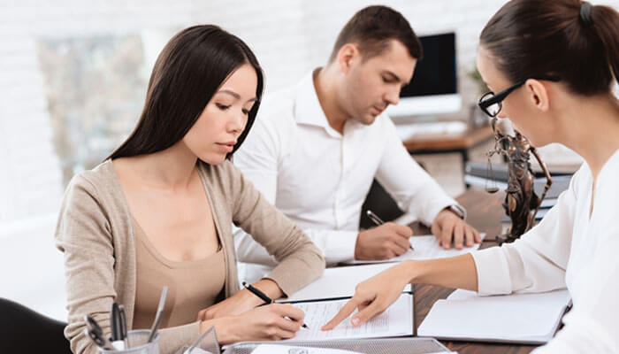 Property Settlement After Divorce: A couple working through legal documents with a lawyer, focusing on the legal intricacies involved in dividing assets during divorce proceedings