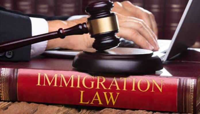 Immigration Lawyer in London working on a laptop with a gavel and an immigration law book in the foreground