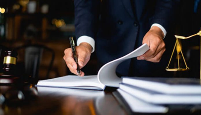 Attorney reviewing legal documents in office with justice scales, showing how the lawyer you choose can shape your case results.