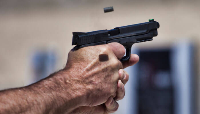 Hand firing a semi-automatic pistol at a shooting range, highlighting training and safety practices for New Gun Owners.