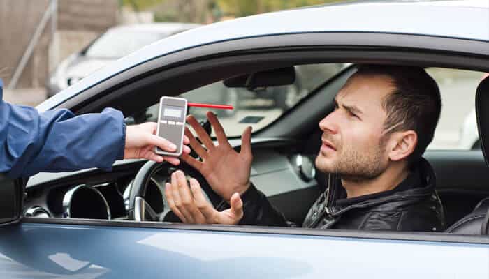 Driver stopped for a breathalyzer test during a DUI arrest, showing police procedure and legal consequences.