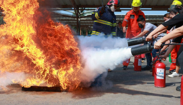 Fire safety training session where participants are using fire extinguishers, demonstrating the role of regulatory bodies in ensuring safety standards and proper emergency response protocols.