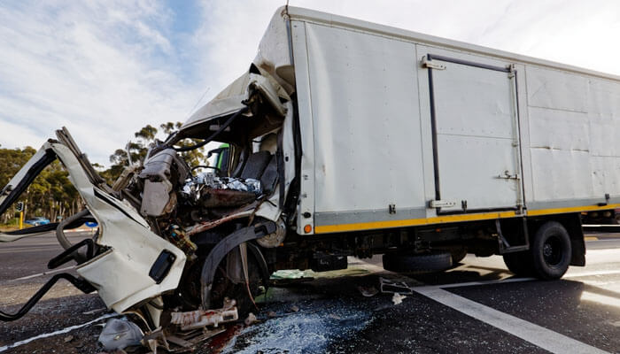 Severely damaged white truck after a road collision, highlighting the importance of legal help from a Truck Accident Attorney in Melville for accident victims.