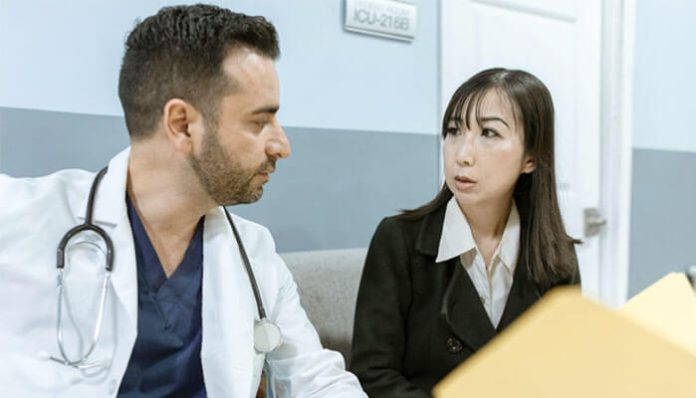 A doctor discussing medical malpractice concerns with a woman in a hospital hallway, highlighting patient rights and legal implications.
