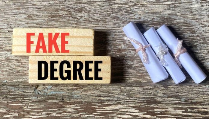Wooden blocks with the words “Fake Degrees” beside rolled-up fake diplomas tied with strings, symbolizing the risks of using fake academic degrees.