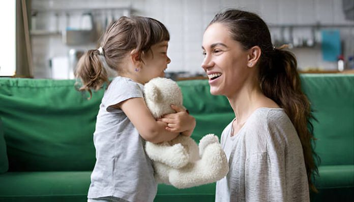 Happy mother with adopted daughter holding a teddy bear, symbolizing the joy of adopting a child in Florida