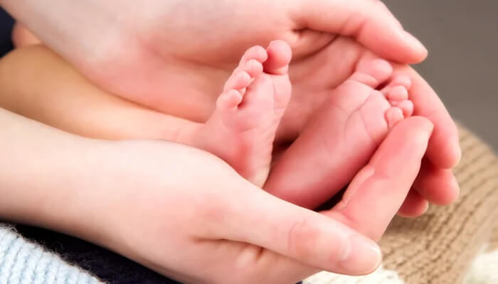 Close-up of a parent’s hands gently holding a newborn’s feet, symbolizing protection, care, and awareness of birth injury risks.