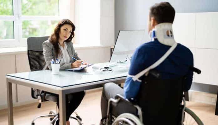 A lawyer consults with an injured client in a wheelchair, discussing evidence and compensation related to Personal Injury Claims.