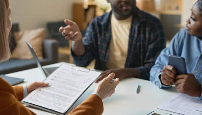 A legal advisor discusses insurance and liability paperwork with clients, highlighting how Motorcycle Laws affect accident claims and compensation across states.