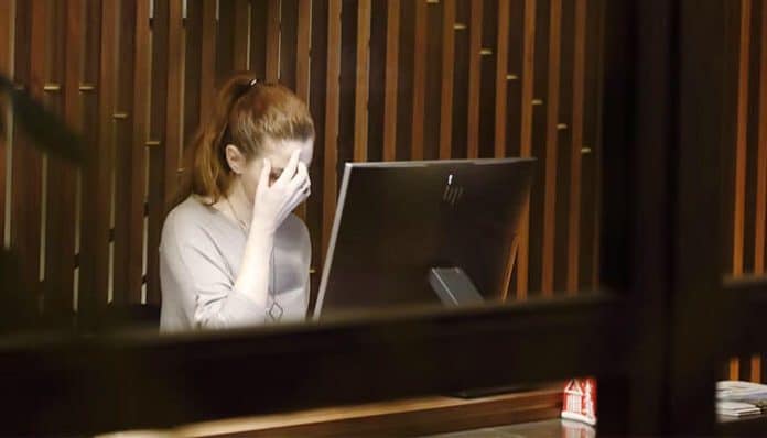 stressed female employee sitting at her desk with her hand on her face, symbolizing the emotional challenges