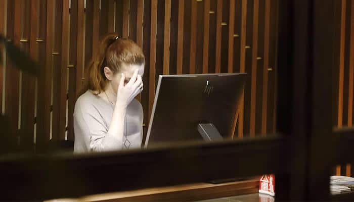 stressed female employee sitting at her desk with her hand on her face, symbolizing the emotional challenges