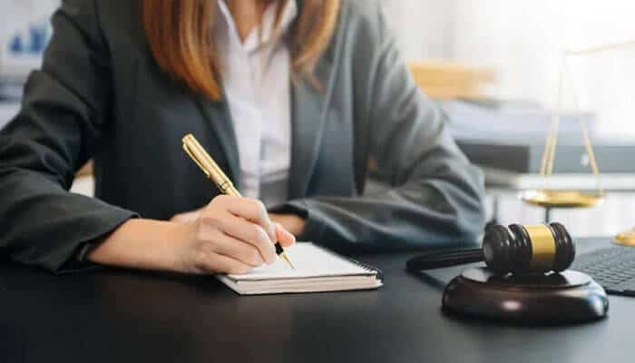 Layoff process for employers concept — a business professional writing legal notes beside a gavel, symbolizing