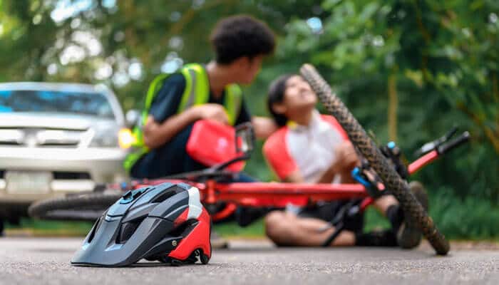Injured cyclist receiving help after a road accident with a car, highlighting the need for a Bicycle Injury Claim.