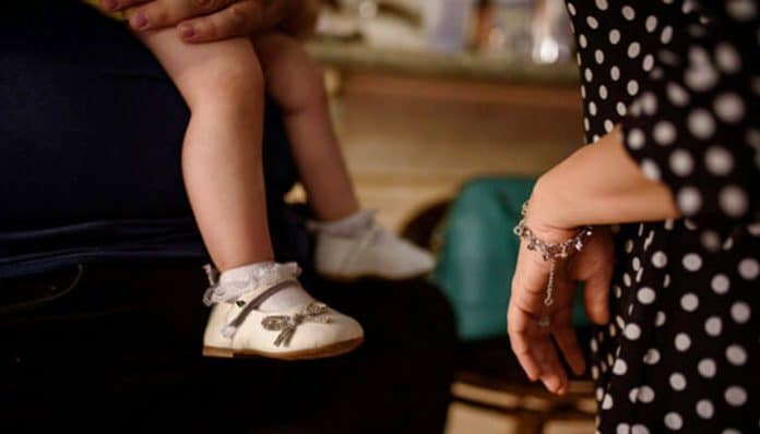 A child sitting on a parent’s lap while another adult stands nearby, symbolizing custody disputes and family challenges linked to Domestic Violence Charges in Florida.