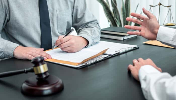 Lawyer reviewing documents with a client about the Direct Fairways Lawsuit, showing legal papers, a gavel, and scales of justice on the desk.