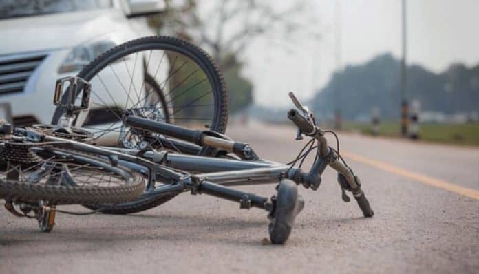A damaged bicycle lying on the road after a bicycle accident involving a car, highlighting the importance of road safety and legal help for injured cyclists.