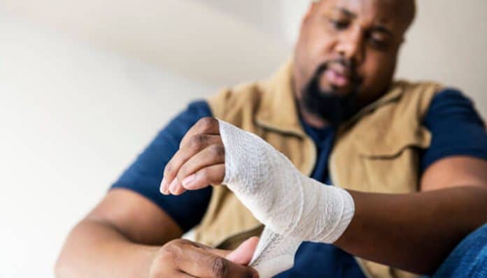 A man carefully wrapping a bandage around his injured hand, illustrating the type of injury that might lead to filing a Personal Injury Claim.