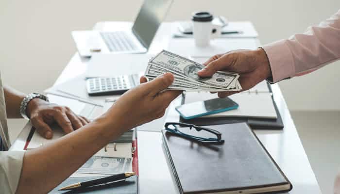 A person receiving a stack of cash during a meeting, representing a settlement or compensation related to a Personal Injury Claim.