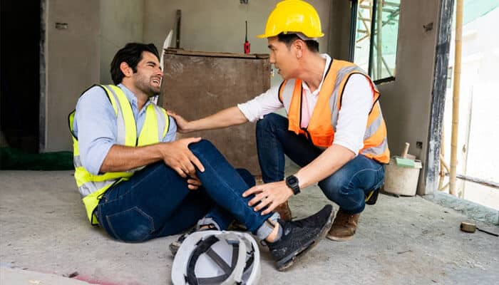 Establishing the Link Between Work and Injury - Myleagalopinion - My Legal Opinion A construction worker suffering a workplace injury on-site while a coworker assists, highlighting the need for safety and legal support.