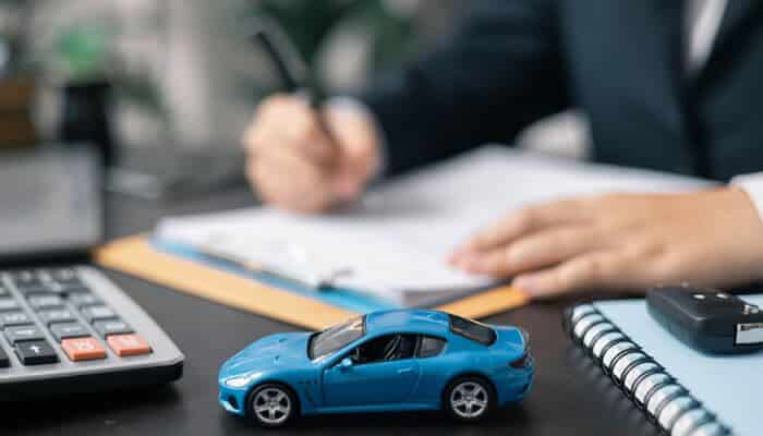 Handling Insurance Companies - Myleagalopinion - My Legal Opinion A Car Accident Lawyer reviewing case paperwork at a desk with a toy car and calculator symbolizing legal and financial aspects after a car crash.