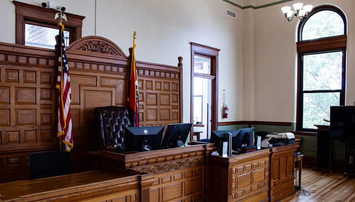 Inside a courtroom with wooden furniture, judge’s bench, flags, and computer monitors — representing the role of personal injury witness statements in legal proceedings.
