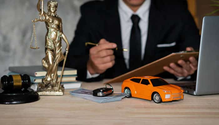 A Car Accident Lawyer reviewing documents at a desk with legal symbols and a model car, representing legal help after an auto accident.