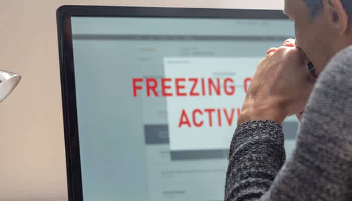 A person viewing a screen with a Freezing Account s Activity warning, illustrating the impact of a freeze on accounts and the importance of understanding why and how it happens.