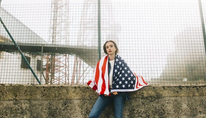 A young woman wrapped in an American flag, symbolizing the legal challenges immigrants face in the United States.