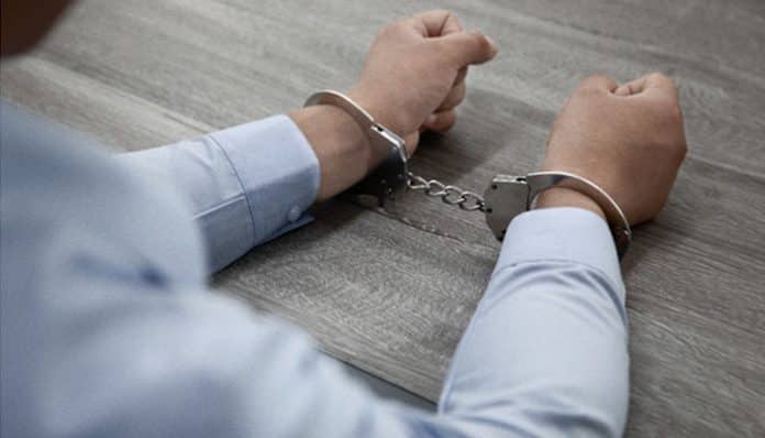 A person in handcuffs sitting at a table, symbolizing a criminal arrest and the importance of knowing your legal rights after being detained.
