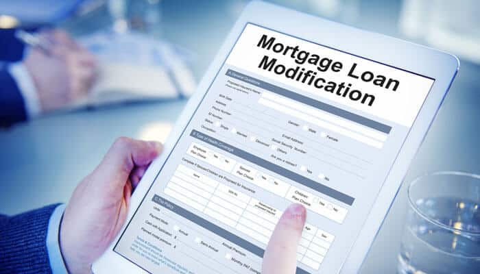 A person reviewing a Mortgage Loan Modification form on a tablet, emphasizing the importance of understanding mortgage loan modification options for financial stability.