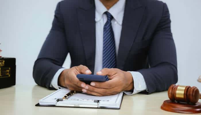 Car accident lawyer reviewing case details on a smartphone, highlighting the role of modern communication in managing car accident claims and client interactions.