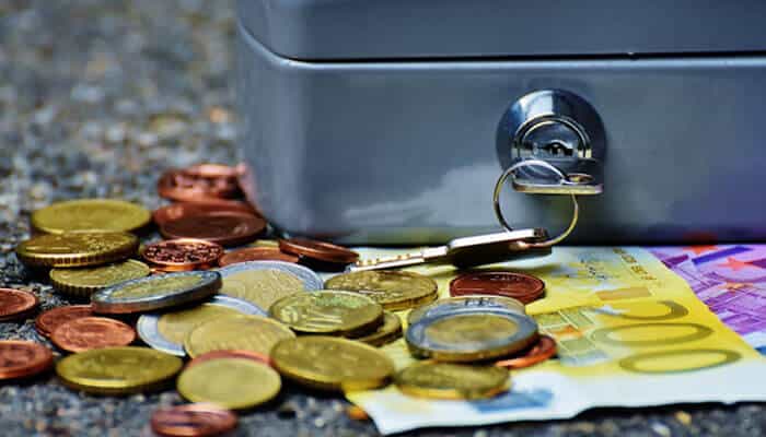 A close-up image of coins and currency beside a locked cash box, symbolizing smart money management and financial discipline — representing Smart Business Leaders on Personal Saving Habits.