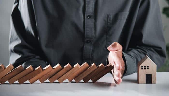 Person blocking falling wooden blocks to protect a house, symbolizing Premises Liability and responsibility for maintaining safe property conditions.