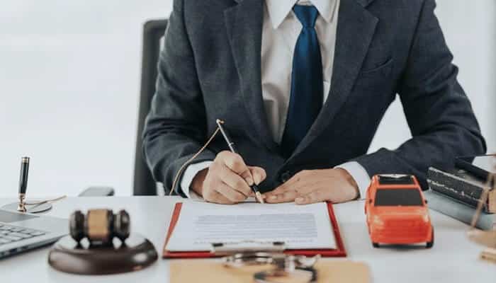 Alt Text: Car accident lawyer reviewing documents in an office, emphasizing the importance of experience and legal expertise in handling car accident claims and securing settlements.