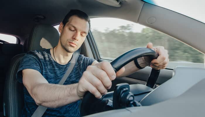 Driver falling asleep at the wheel, showing the dangers of drowsy driving car accident and fatigue-related crash risks.

