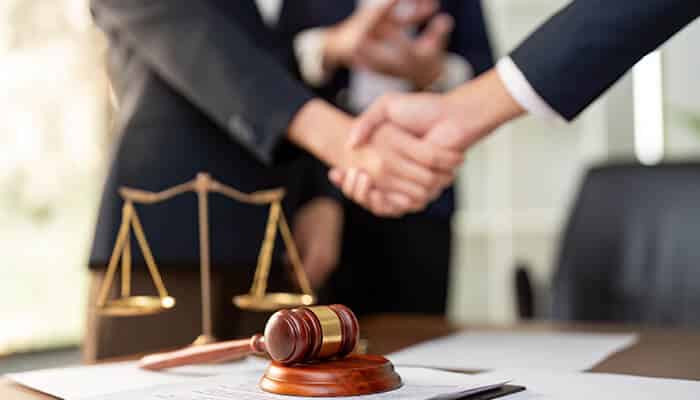 Communication and Availability - Myleagalopinion 1 - My Legal Opinion A criminal defense attorney shaking hands with a client, with a gavel and scales of justice in the foreground, symbolizing successful legal representation.